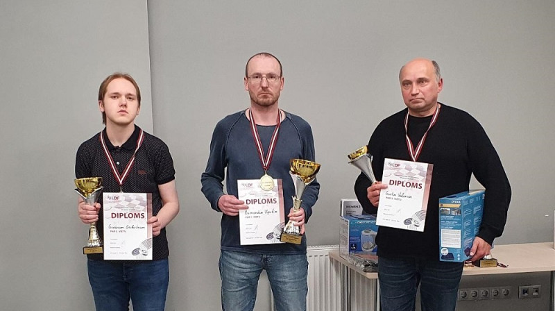 Pirmo trīs vietu ieguvēji ar čempionu R.Vipuli centrā. G.Valneris (no labās) un G.Gribuška (no kreisās). Foto: Latvijas Dambretes federācija.